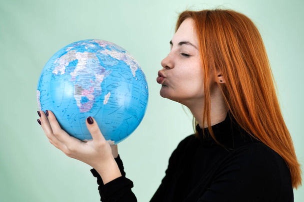 Portrait of a happy young woman holding geographic globe of the world in her hands. Travel destination and planet protection concept. - Фото, зображення