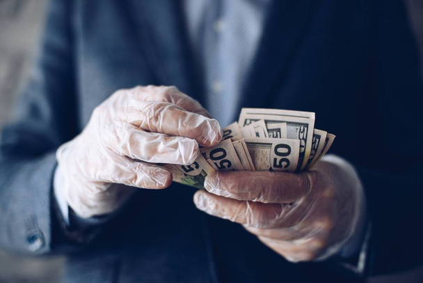 Człowiek licząc amerykańskie dolary pieniądze banknoty w rękawicach ochronnych lateksowych. - Zdjęcie, obraz