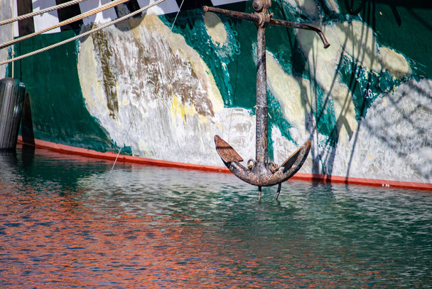 L'ancora di una barca squallida si vede appesa sopra l'acqua increspata prima dello scafo della barca
. - Foto, immagini