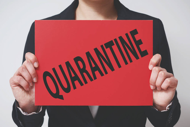 a businesswoman in a jacket holds a red placard with the words quarantine. Concept of the economy's response to a new coronavirus covid-19 2019-ncov. - Fotó, kép
