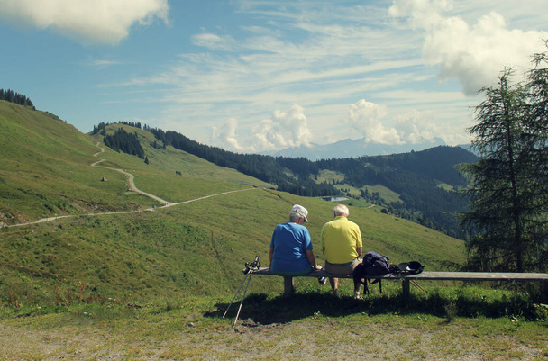 Dos ancianos descansan después de caminar en las montañas de verano
 - Foto, imagen