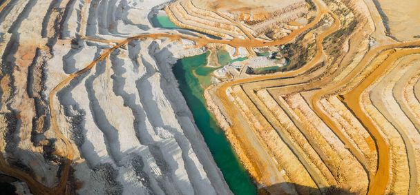 Blick von oben auf einen Sandbruch. Arial Blick auf einen Abbau natürlicher Ressourcen oder Erze. Grüner Fluss trennt weiße und gelbe Sandstrände. Wasserlinie mit zwei Arten von Land. Natürliche Textur - Foto, Bild