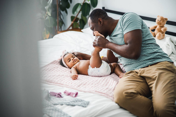 Afro American father playing with newborn daughter at home - Foto, Imagen