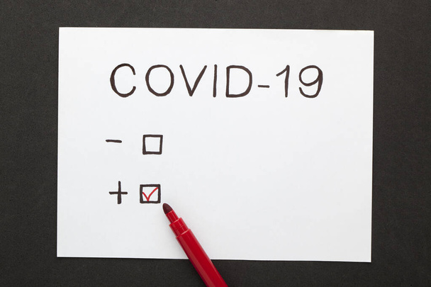 Covid-19 Coronavirus teszt fehér papírlapon fekete alapon - Fotó, kép