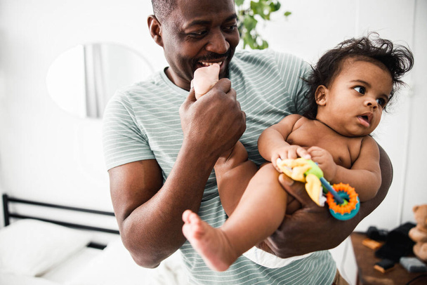 Smiling Afro American man holding newborn daughter in his arms - Foto, Bild