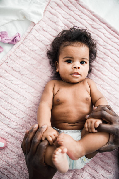 Afro American man holding legs of cute newborn child - Fotografie, Obrázek