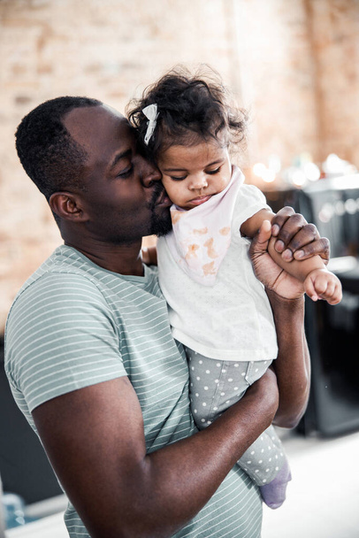 Afro American man holding newborn daughter and kissing her cheek - Фото, зображення