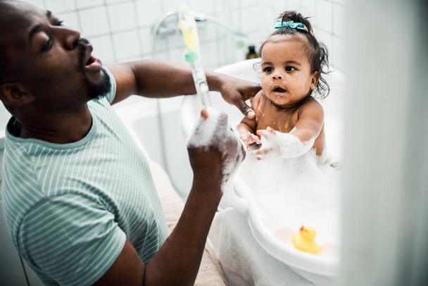 Cute newborn child taking bath and playing with daddy - Фото, изображение