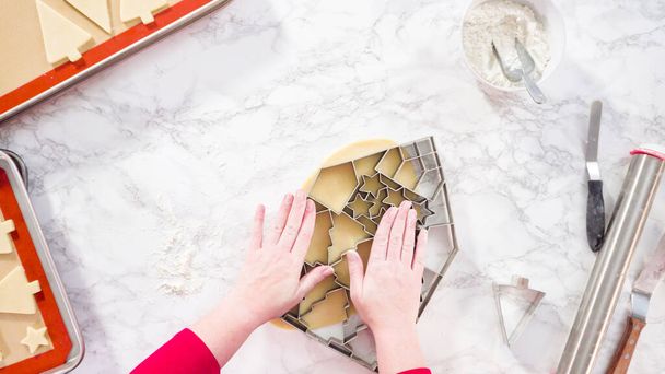 Leżeć płasko. Wycinanie ciasteczek z cukrem gigantycznym Christmas cookie cutter. - Zdjęcie, obraz