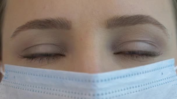 Jonge vrouw gezicht dragen beschermende medische gezichtsmasker in quarantaine tijd voor virusinfectie preventie en bescherming. Angst, paniek over het epidemische virus - Video