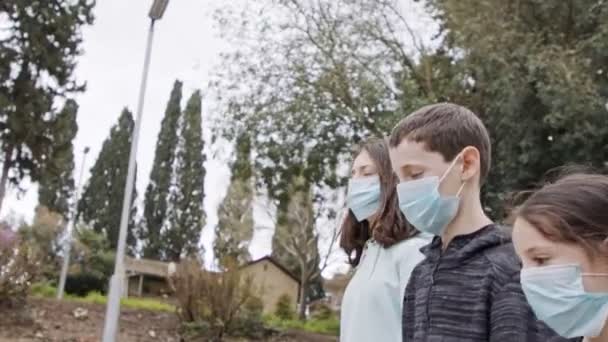 Coronavirus pandemic - kids walking outdoors with face masks to avoid contagion - Felvétel, videó