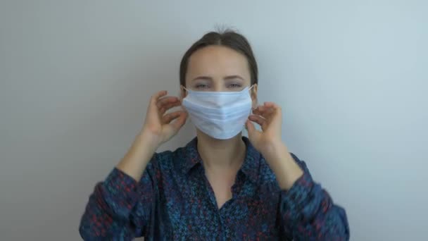 Young woman in protective medical mask is sneezing. Female wearing face mask is coughing. Coronavirus and flu epidemic protection. Pandemic protection of the Covid-19 coronavirus - Video, Çekim