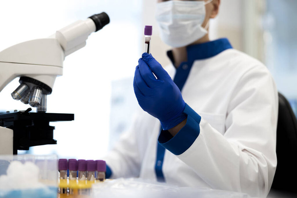 Männlicher Forscher hält Laborröhrchen mit Blutprobe - Foto, Bild