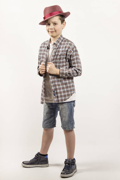 menino alegre feliz isolado em um fundo branco. Um menino de camisa e chapéu xadrez
. - Foto, Imagem