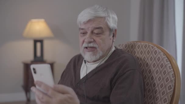 Portrait of confident old Caucasian man talking at selfie camera. Senior retiree having video call indoors. Leisure, lifestyle, modern wireless technologies. - Footage, Video