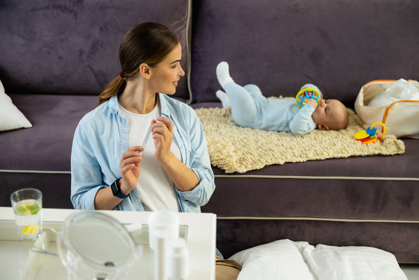 Smiling pretty lady looking at her baby in room - Фото, зображення