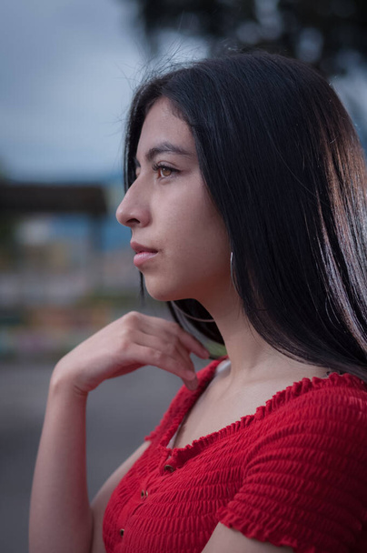 retrato de chica latina con el pelo largo y negro con la mano cerca de la cara mirando a un lado
 - Foto, imagen