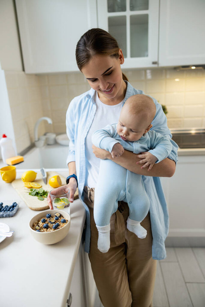 Smiling lady standing with her kid in the kitchen at home - Foto, Imagem