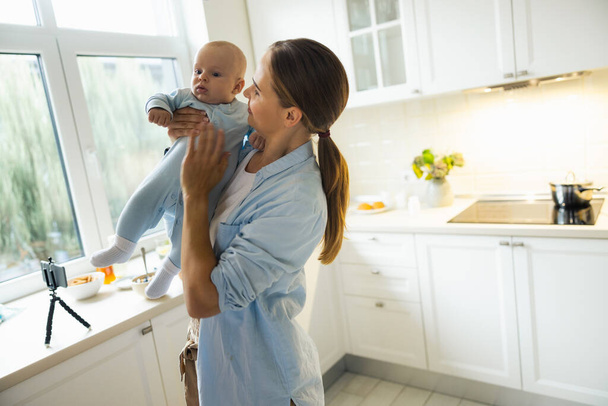 Όμορφη μαμά απολαμβάνει το χρόνο με το μωρό της στην κουζίνα - Φωτογραφία, εικόνα