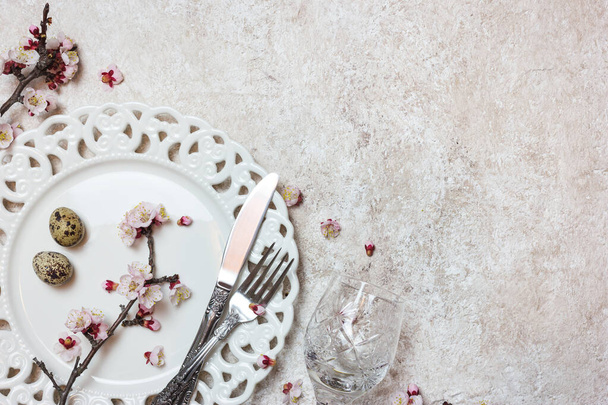 Beautiful festive table setting with spring blossoming branches on light textured background. Top view with copy space. - Foto, Imagem