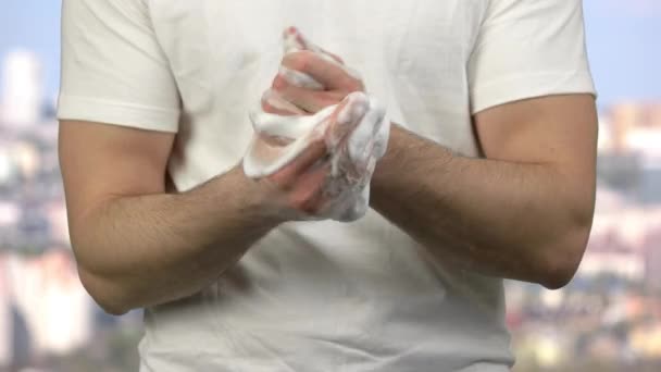 Portret van een jongeman die zijn handen schoonmaakt met zeepschuim. - Video