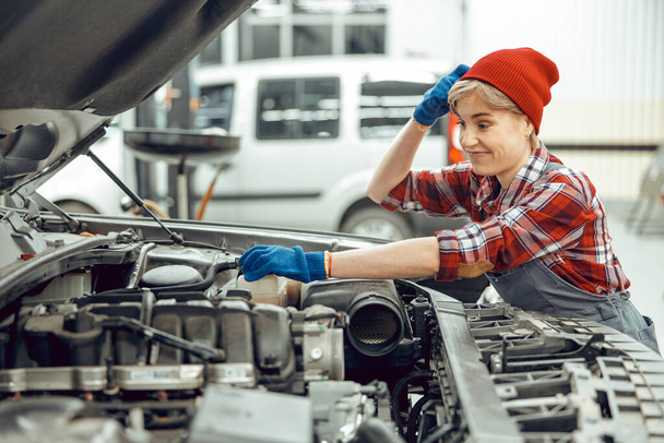 Puzzled female technician leaning on an automobile - Foto, immagini