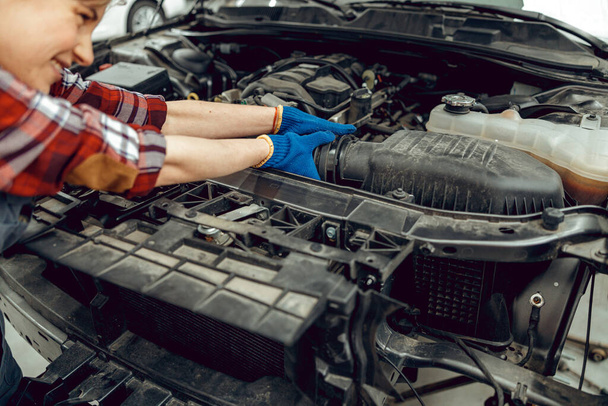 車の冷却ホースを交換する女性技術者 - 写真・画像