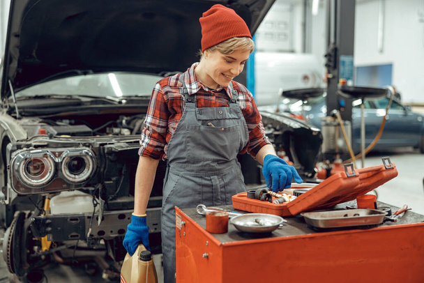 Car mechanic in a cap choosing instruments - Foto, Bild