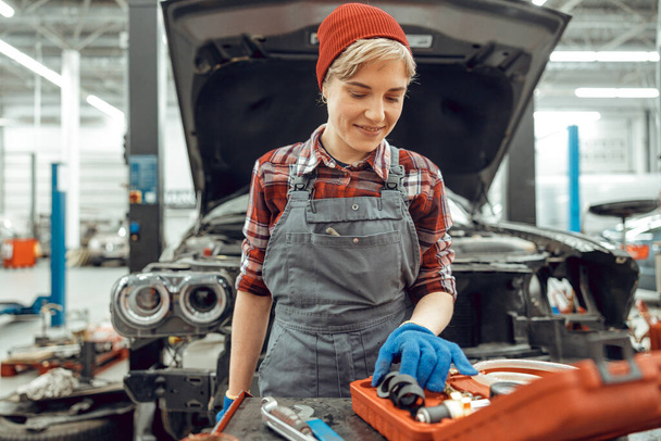 Pleased Caucasian female mechanic choosing rubber spacers - Photo, Image