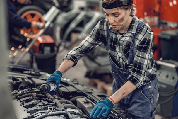 Mechanic performing engine diagnostics in a repair shop - Фото, изображение