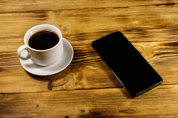 Kuppi kahvia ja älypuhelin puinen pöytä
 - Valokuva, kuva