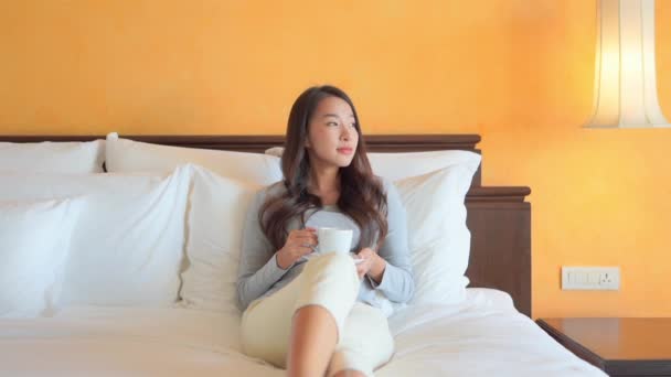 Portrait belle jeune femme asiatique avec tasse de café sur le lit dans la chambre à coucher intérieur - Séquence, vidéo