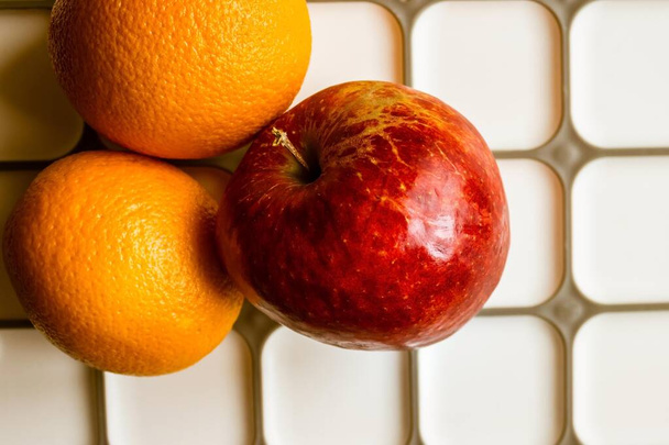 ライトキッチンボード上のアップルと2つのオレンジ。デザート、軽食、食事、適切な栄養。トップビュー、昼間側の照明. - 写真・画像