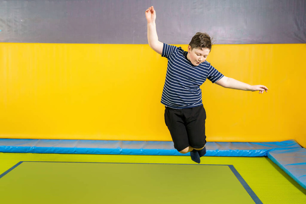 Surpoids mignon petit garçon sautant sur trampoline à l'intérieur dans un centre sportif pour enfants
 - Photo, image