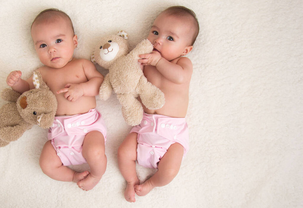 Baby twins girls with cloth diaper on a bed - Fotó, kép