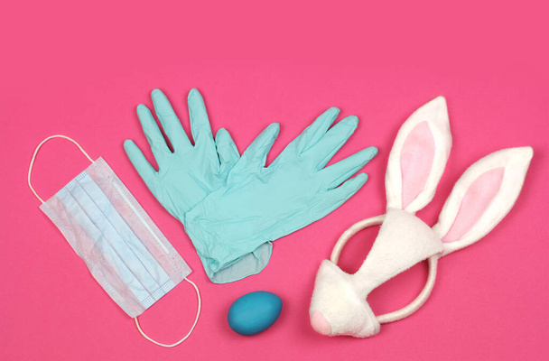 húsvéti tojás és nyuszi maszk, orvosi kesztyű és orvosi maszk, vírus vagy koronavírus karantén és védelem nyaralás előtt, felülnézet rózsaszín háttéren fénymásoló hellyel    - Fotó, kép