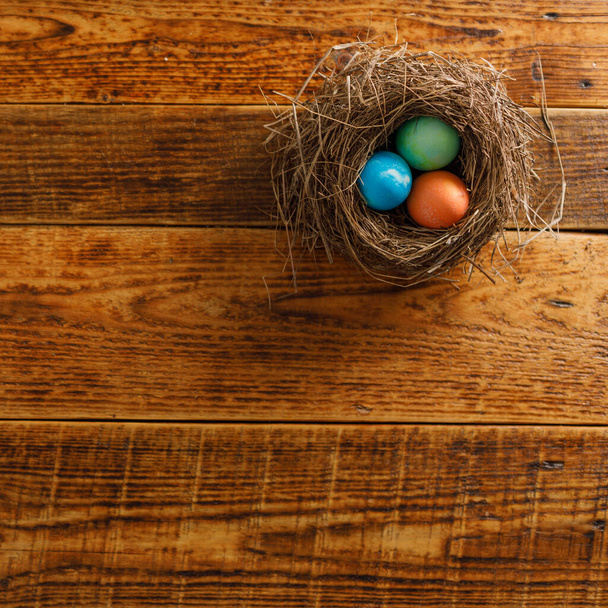 La naturaleza muerta de los huevos de Pascua en el nido del pájaro sobre el fondo de madera. Rústico. Concepto de celebración de Pascua. Copiar espacio. Puesta plana
 - Foto, imagen