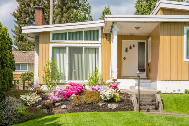 Вхід в красивий сімейний будинок з зеленим газоном спереду
 - Фото, зображення