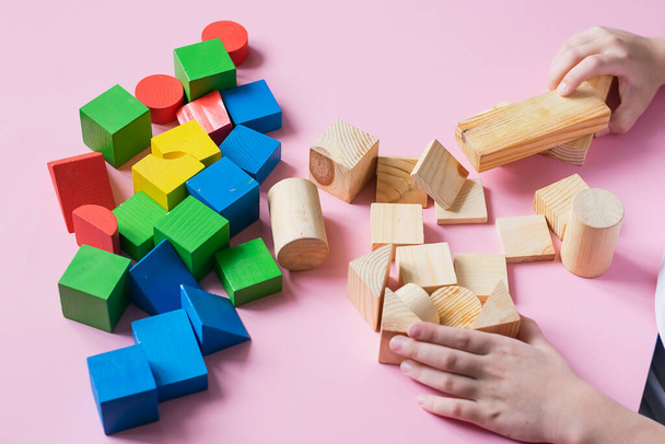 The child plays collects wooden colored cubes constructor. Education concept for special children learning. - Photo, Image