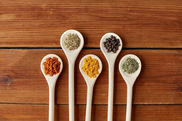 spoons with different spices on wooden table - Foto, afbeelding