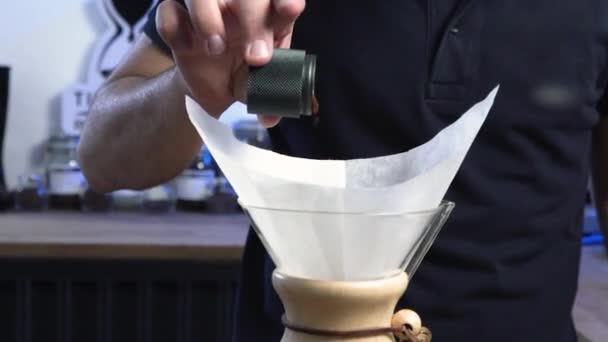 Barista kaataa tuoretta jauhettua kahvia käsin hiomakoneesta Chemexiin
 - Materiaali, video