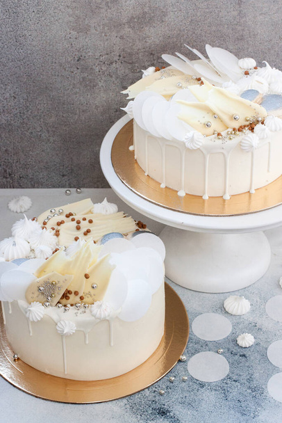 Elegant white cake decorated with melted white chocolate, meringues, waffle paper and macaroons. - Fotoğraf, Görsel