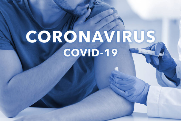 Doctor vaccinating man in clinic. Concept of Coronavirus epidemic - Фото, изображение