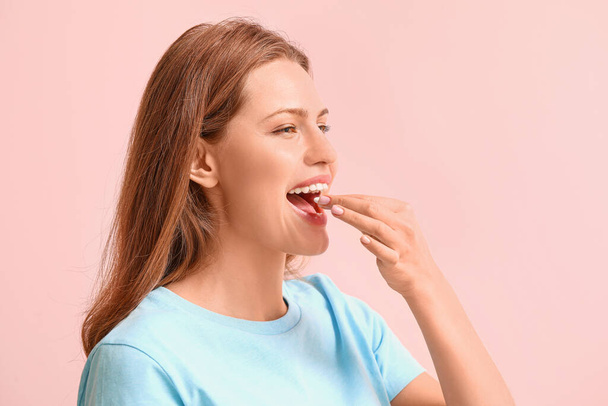 Young woman with chewing gum on color background - Photo, Image