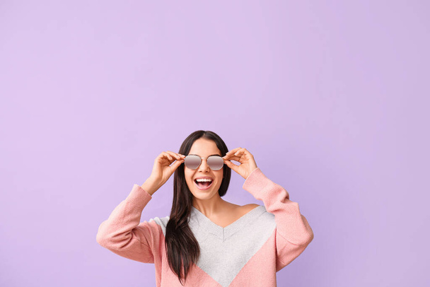 Young woman with stylish sunglasses on color background - Foto, afbeelding