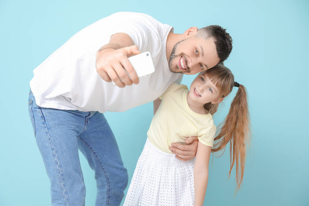 Father and his little daughter taking selfie on color background - Foto, Imagem