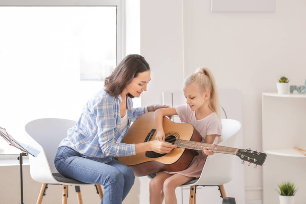 Private music teacher giving guitar lessons to little girl at home - Photo, image