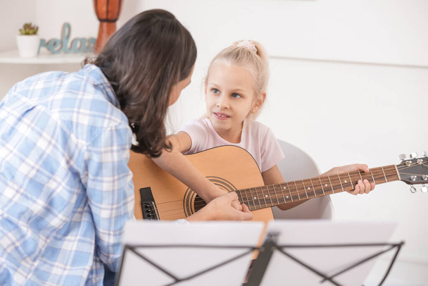 Privater Musiklehrer gibt kleinem Mädchen zu Hause Gitarrenunterricht - Foto, Bild
