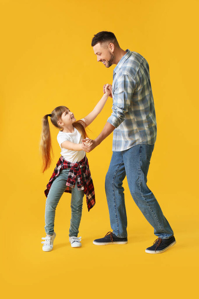 Father and his little daughter dancing against color background - Photo, Image