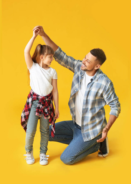 Father and his little daughter dancing against color background - 写真・画像